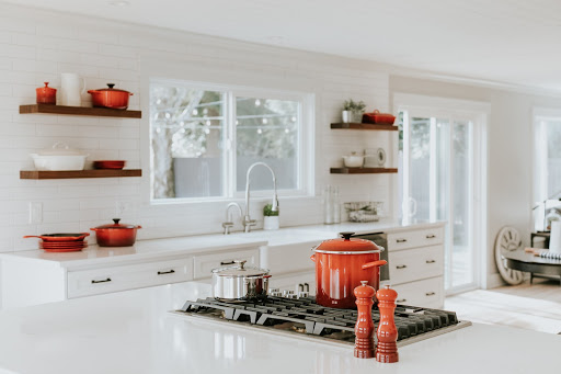 a large kitchen with white countertop and orange accessories