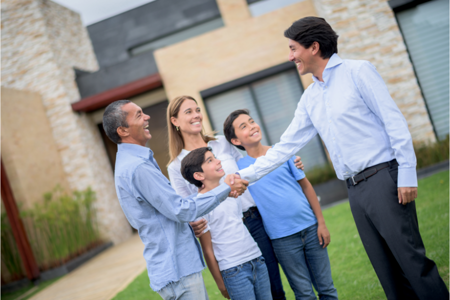 a family shaking hands with a realtor in front of a property